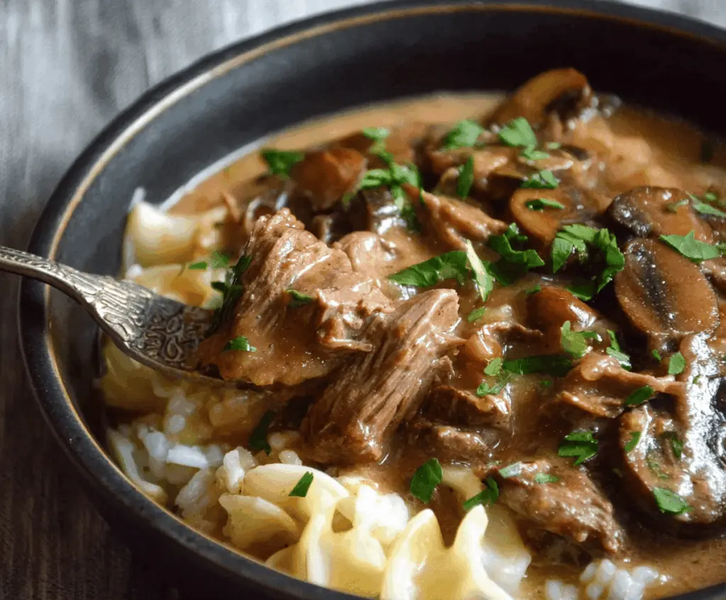 Creamy slow cooker beef stroganoff stew with tender beef chunks, mushrooms, and savory sauce served in a bowl