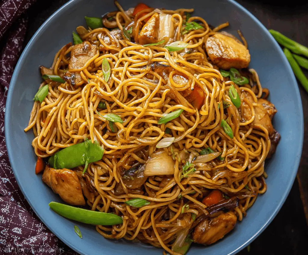 Delicious Chicken Teriyaki Noodles garnished with green onions on a white plate.