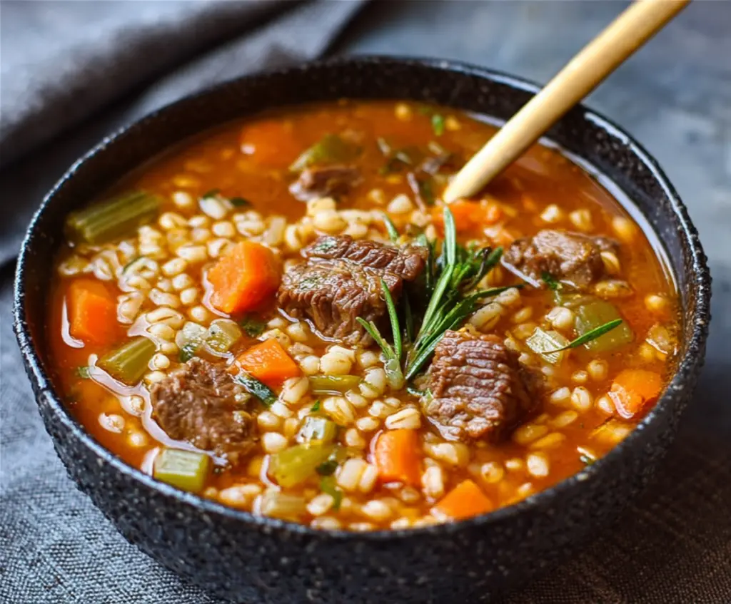 Warm bowl of hearty beef and barley soup with vegetables and herbs, perfect for a comforting meal.