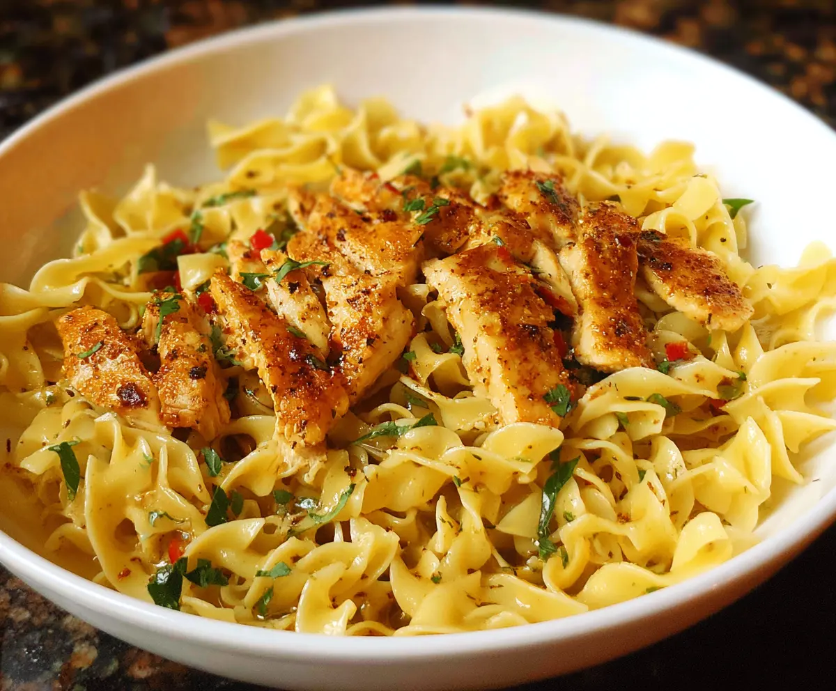 Creamy chicken buttered noodles garnished with herbs on a white plate