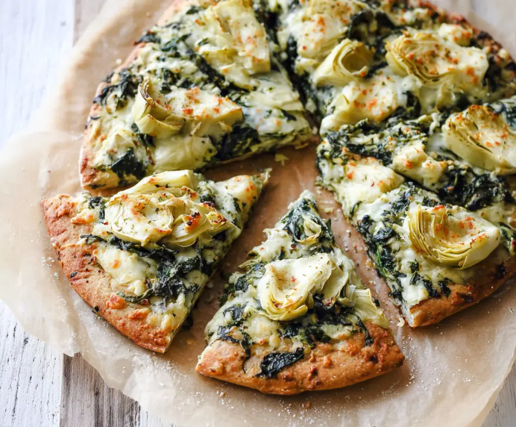 Delicious high protein spinach and artichoke pizza topped with fresh greens and melted cheese.