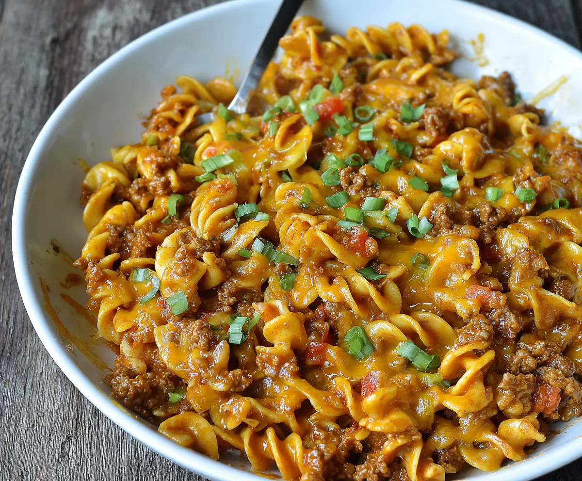 Delicious Cheesy Taco Pasta topped with melted cheese and fresh herbs, ready to serve.