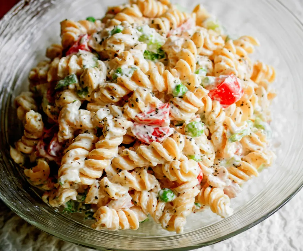 Delicious creamy pasta salad with fresh vegetables and herbs, perfect for summer picnics.