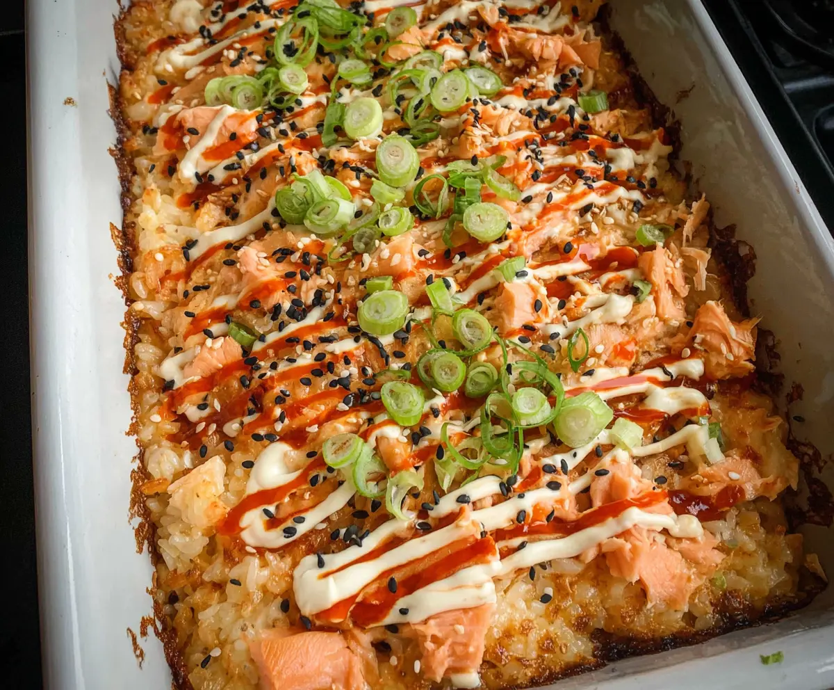 Spicy Salmon Sushi Bake served in a ceramic dish with sesame seeds and green onions on top.