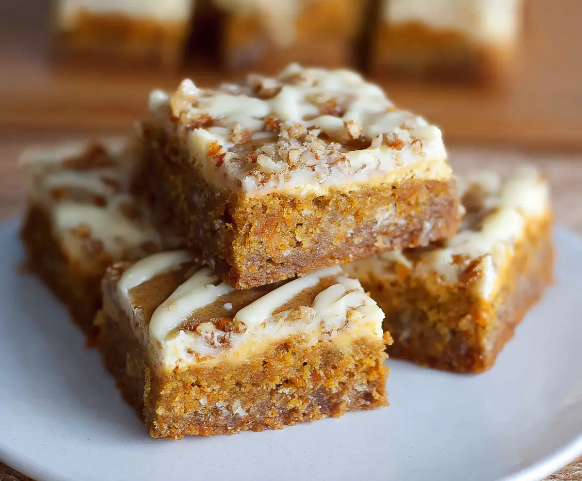 Delicious homemade carrot cake bars with cream cheese frosting on a rustic plate.